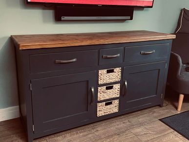 a dark grey sideboard with 3 draws on top 2 doors and 3 pull out baskets