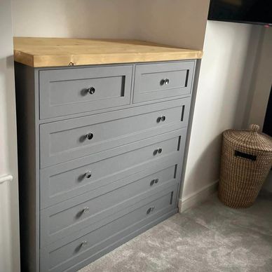 a grey chest of draws 2 smaller draws above 4 long draws with a light oak top