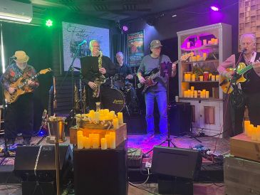 A band performing live on stage with colorful lights and candles.