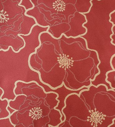 Red fabric with embroidered beige floral patterns.