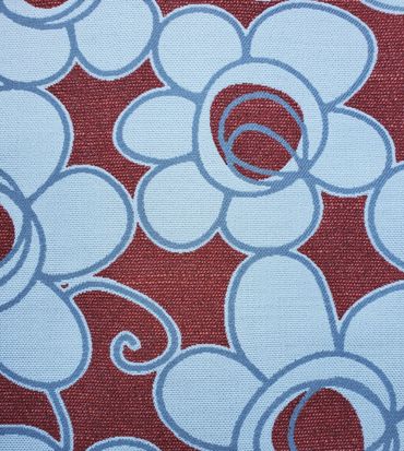 Close-up of a fabric with blue floral patterns on a red background.