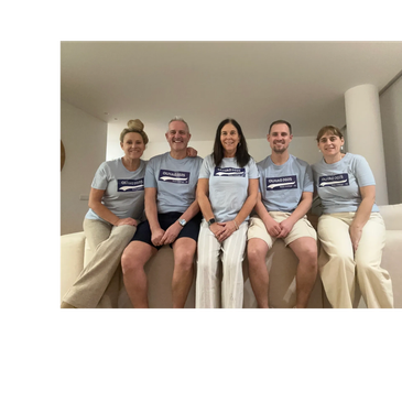 Five people sitting on a couch, smiling and wearing matching "QUALICONS" t-shirts.
