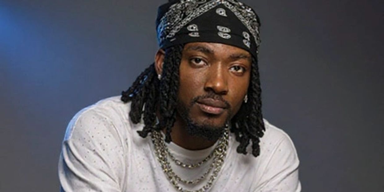 Man with dreadlocks wearing a bandana and chains.