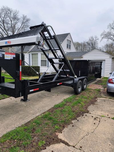 Black trailer parked in front of a house on a driveway.