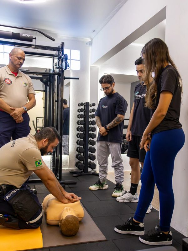 Group learning CPR on a training mannequin in a gym setting.