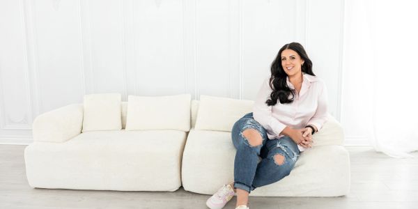 Woman sitting on a white sofa with a smile.