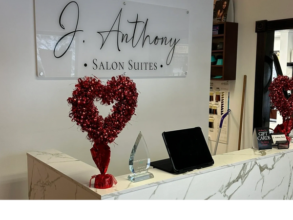 Reception desk of J. Anthony Salon Suites with red heart decoration and tablet.