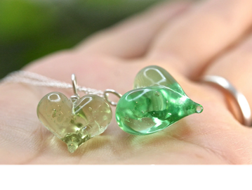 Two heart-shaped glass pendants resting on a hand.