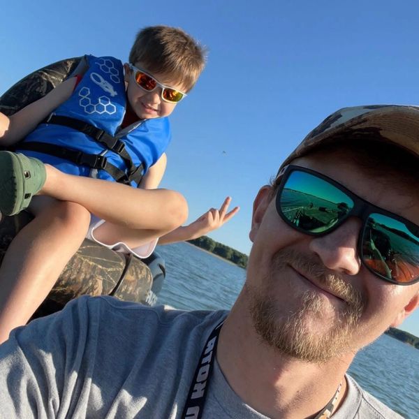 Father and son enjoying a sunny day on the water in a boat. Derek does our air conditioning services, heating and cooling and HVAC solutions