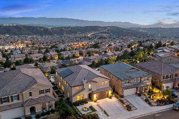 Suburban neighborhood at dusk with houses and distant mountains.