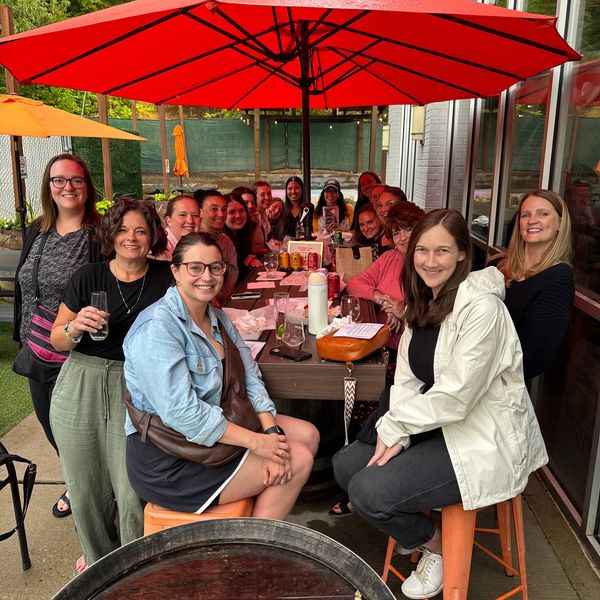Group of friends enjoying a gathering under red umbrellas at an outdoor restaurant.