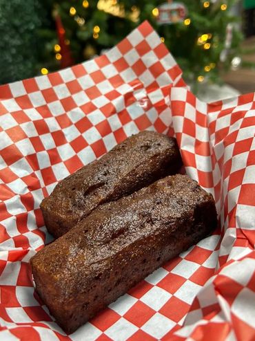 Two chocolate cakes in a basket on top of red and white paper.