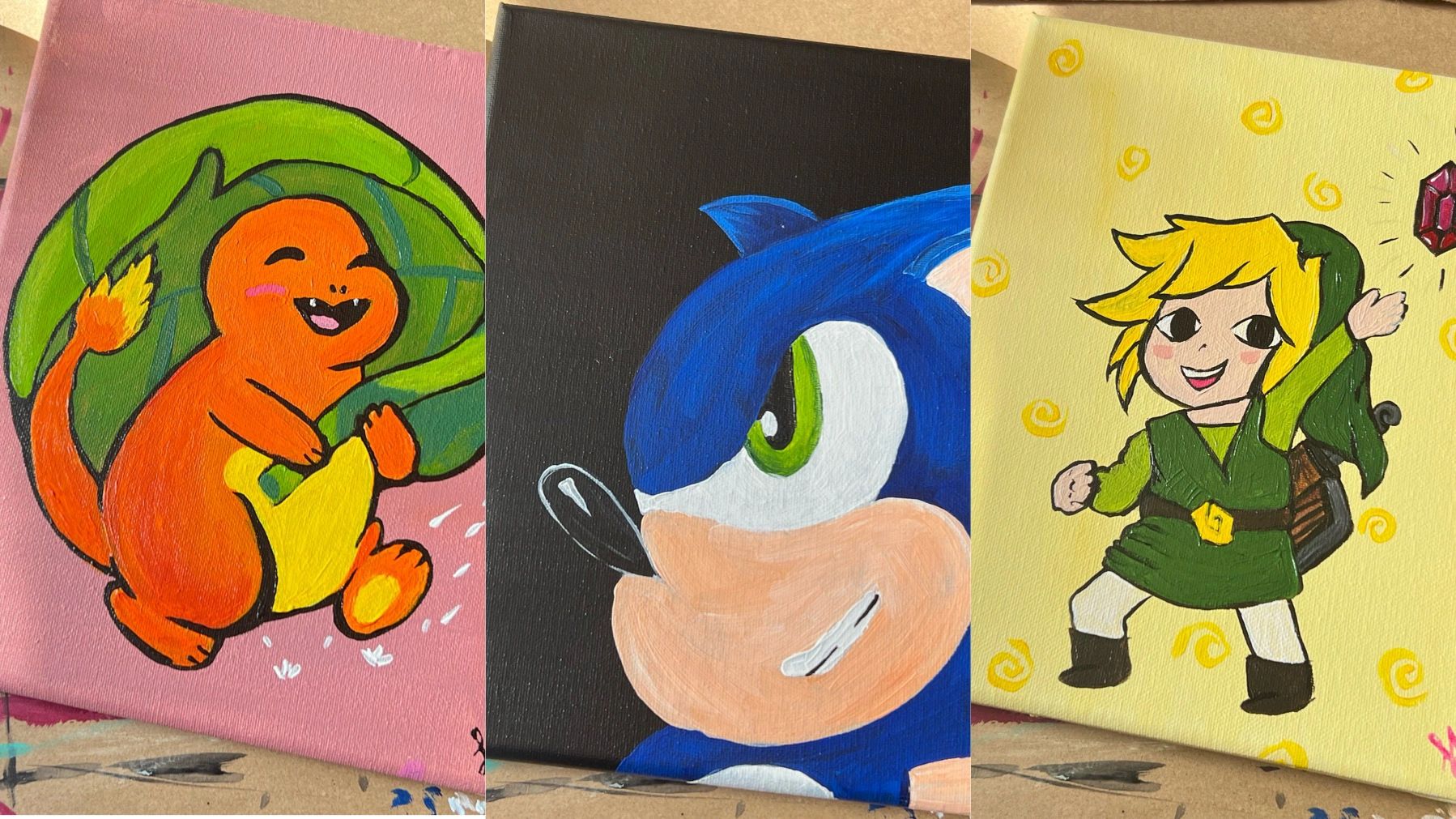 Three paintings of video game characters Charmander, Sonic, and Link.