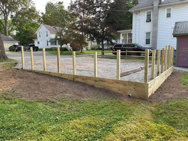 Wooden frame foundation being built for a structure beside a house.