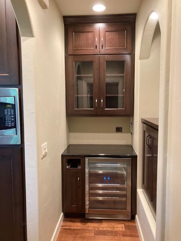 Small bar cabinetry matching existing kitchen stain with side built-in storage nook