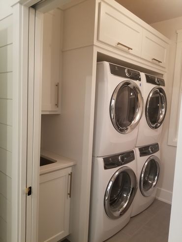 Double built-in washer/dryer units with flip-up door storage above