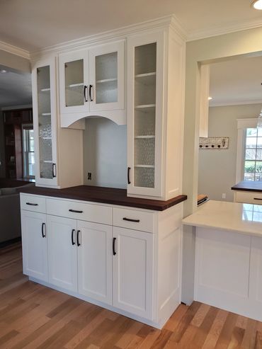 Custom buffet behind kitchen for coffee storage with glass paneled upper cabinet doors