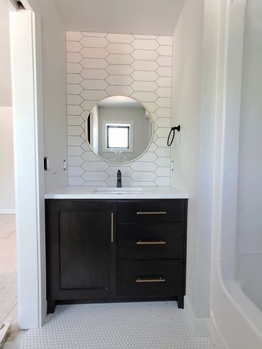 New construction stained maple vanity with tiled wall behind mirror