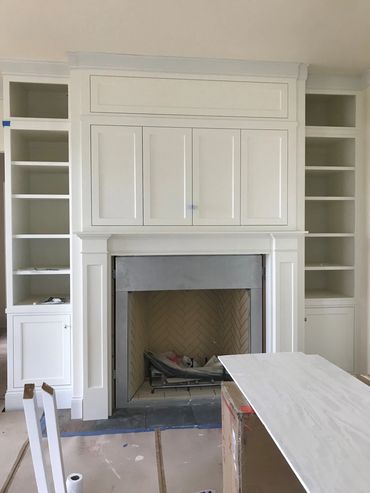 Fireplace built-ins with inset door panels above custom mantel legs