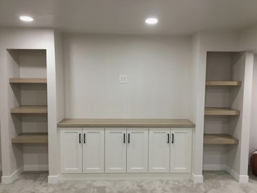Lower level entertainment center with deep floating shelves matching wood countertop