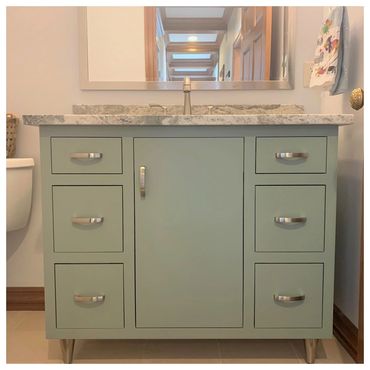 Painted green inset vanity with satin nickel hardware, faucet, and cone-shaped feet