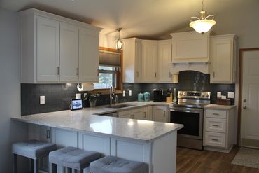 Kitchen remodel with painted white cabinetry and new custom range hood