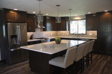 Dark stained maple kitchen cabinets with light toned backsplash and quartz countertops