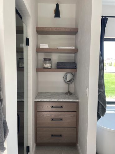 Extra bathroom storage area with floating shelves, cabinet drawers, and marble countertop