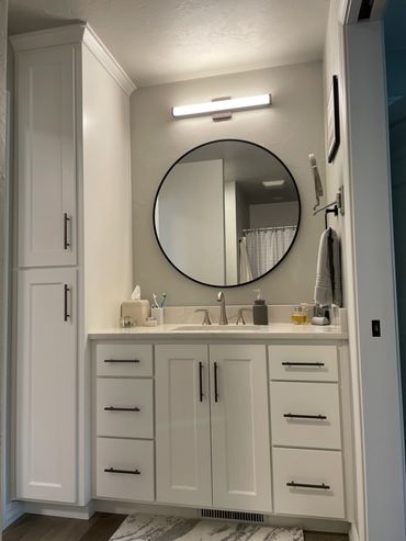 Painted white vanity and linen cabinet with black hardware