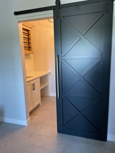X paneled black barn door going into laundry room
