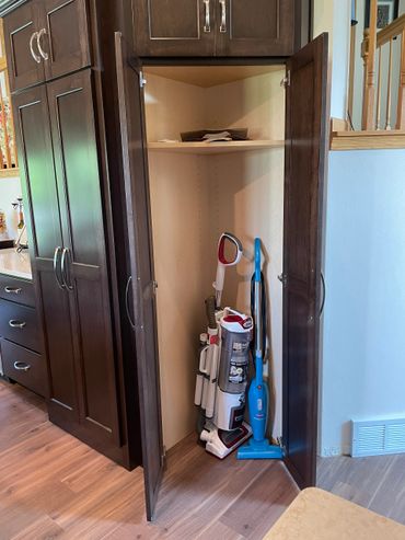 Vacuum storage in angled tall cabinet with adjustable cornered shelf inside