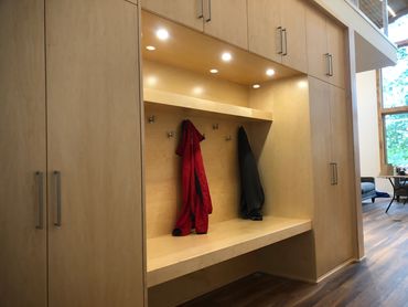 Custom built-in locker in clear maple with tall storage inside of cabinets and floating bench