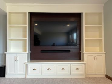 Entertainment center with oak shiplap behind TV and painted built-ins