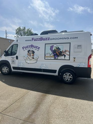 Mobile pet grooming van with playful dog illustrations and website info.