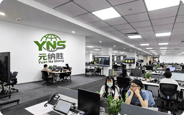 Modern office space with employees working at desks under bright lighting.