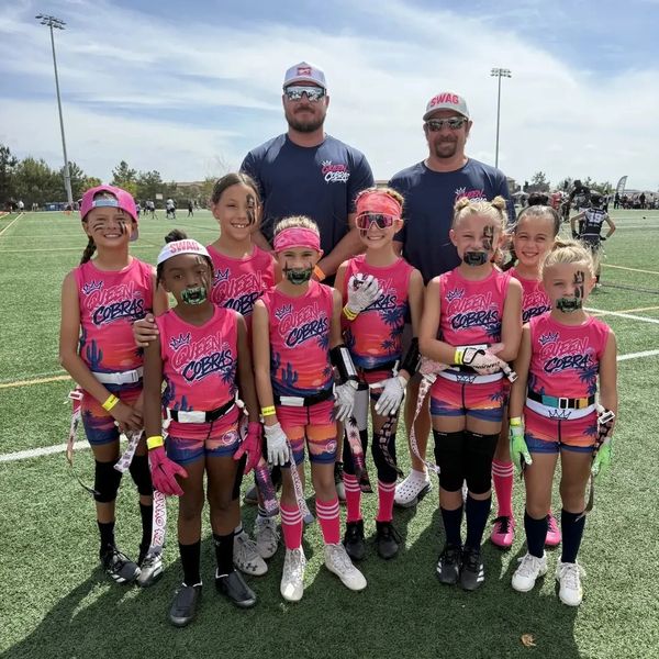 Youth girls football team with coaches posing on the field.