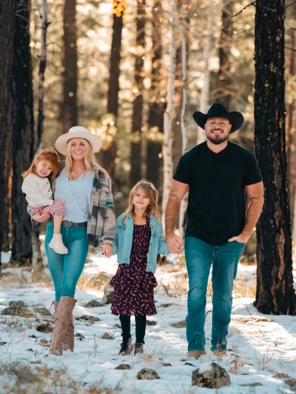 Family walking together in snowy forest.