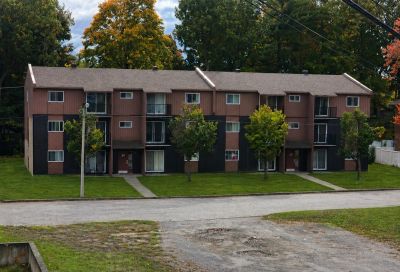 A multi-unit residential building with brown siding and small balconies.