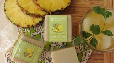 Pineapple cilantro bar soap with sliced fresh pineapple, juice, cilantro sprigs, and tea towel.