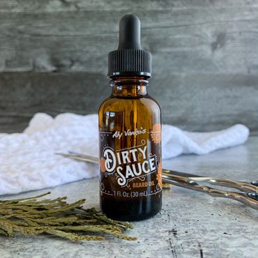 Cedar Dirty Sauce with barber scissors, waffle-weave towel, and cedar tips on wood and concrete.