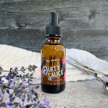 Lavender Dirty Sauce with barber scissors, waffle-weave towel, and cedar tips on wood and concrete.