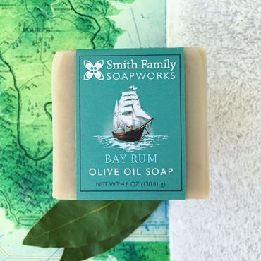 Bay rum bar soap styled with bay leaves, white terrycloth, and map of an island.