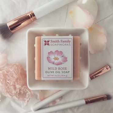 Wild rose bar soap styled with white and rose gold makeup brushes, rose petals, and pink quartz.