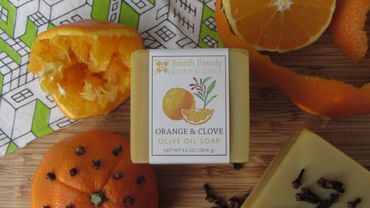 Orange and clove bar soap with tea towel, orange halves, orange rind, cloves, and pomander.