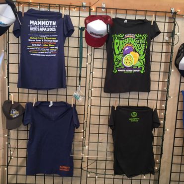 Branded festival t-shirts and baseball hats hanging in the merchandise tent.