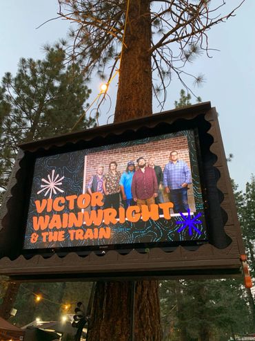 Photo and name of band on a large television monitor: Victor Wainwright & The Train.