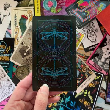 Card held showing the back design. Pile of mismatched cards from other decks in the background.