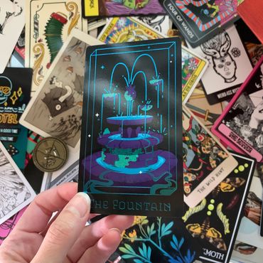 Card held displaying the front side showing turquoise foil glinting in the light.