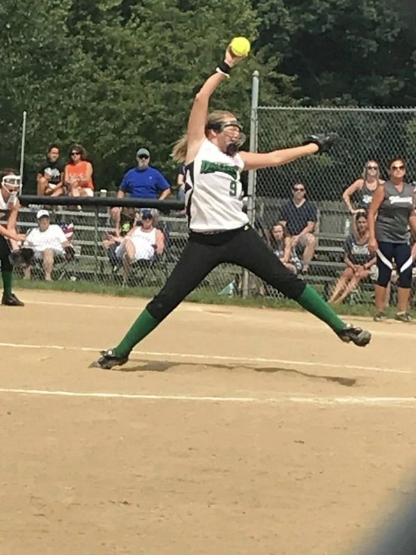 Softball pitcher in mid-throw on a sunny day.