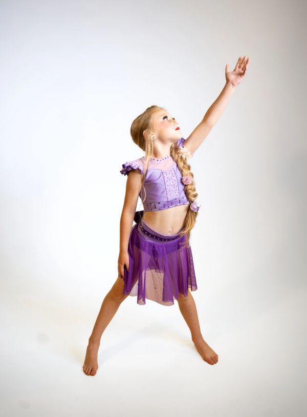 Young girl in a purple dance costume striking a graceful pose.